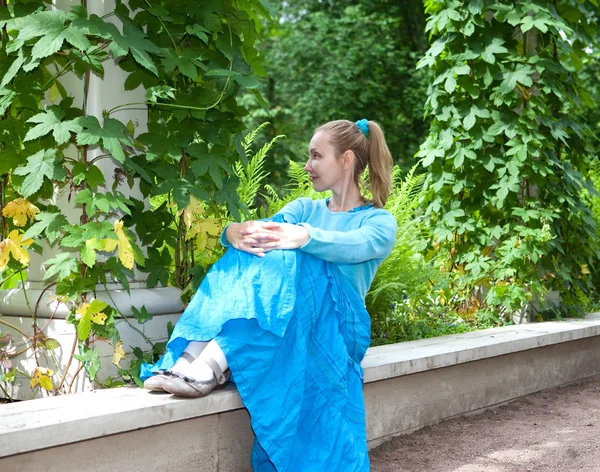アーバーの青いドレスの若い美しい女性絡まった緑ソバカズラ — ストック写真