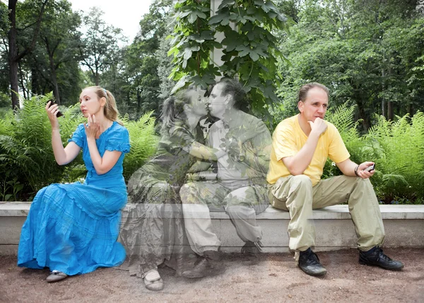 Mujer joven y el hombre se sientan en un banco en el parque por separado, pero en sueños se besan — Foto de Stock