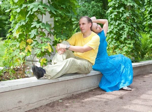 Young happy couple sits in the arbour twined greens — Stock Photo, Image