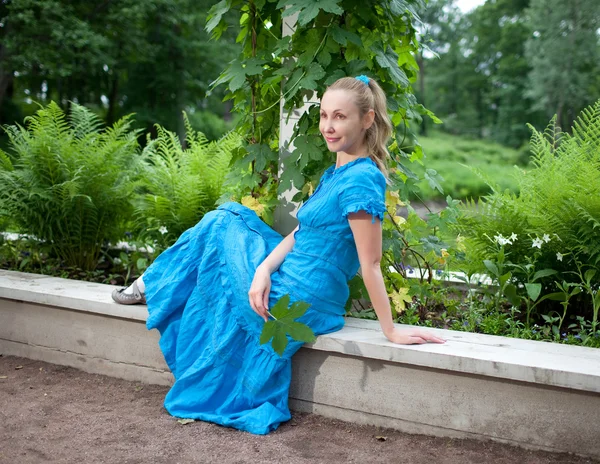 Η όμορφη κοπέλα σε ένα μπλε φόρεμα με την κληματαριά τυλίγεται ένα πράσινο bindwee — Φωτογραφία Αρχείου