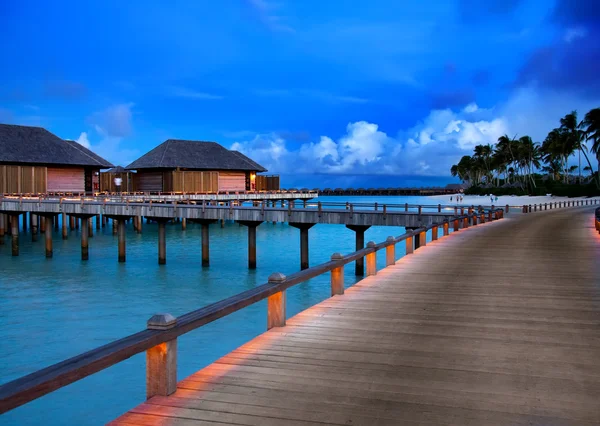 Hus på pålar på vatten vid tiden solnedgången, Maldiverna. — Stockfoto