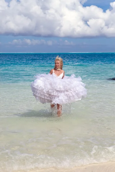 Die junge schöne Frau im Kleid der Braut rennt auf den Wellen des Meeres — Stockfoto