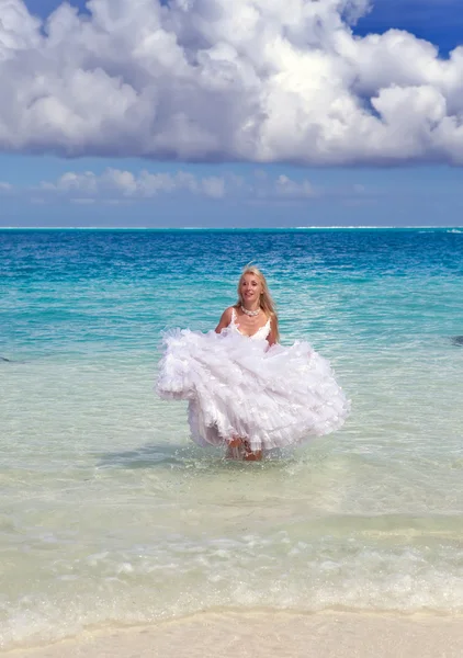 La bella donna giovane in un vestito della sposa corre su onde del mare — Foto Stock