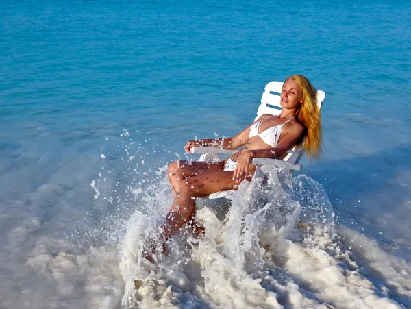 Joven bonita mujer en una silla de playa en el océano — Foto de Stock