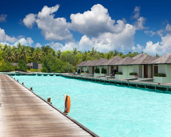 Casas sobre a água do mar tranquila transparente e uma palmeira — Fotografia de Stock