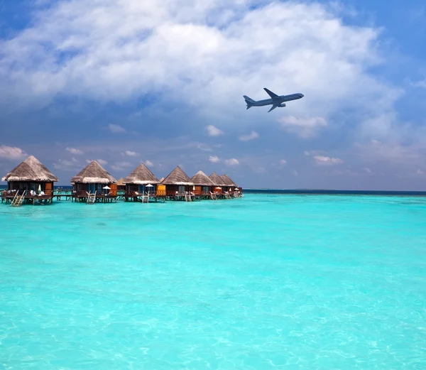 Lodges over water and the plane in the sky - tropical paradise — Stock Photo, Image