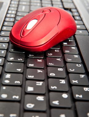 The red computer mouse on the black keyboard clipart