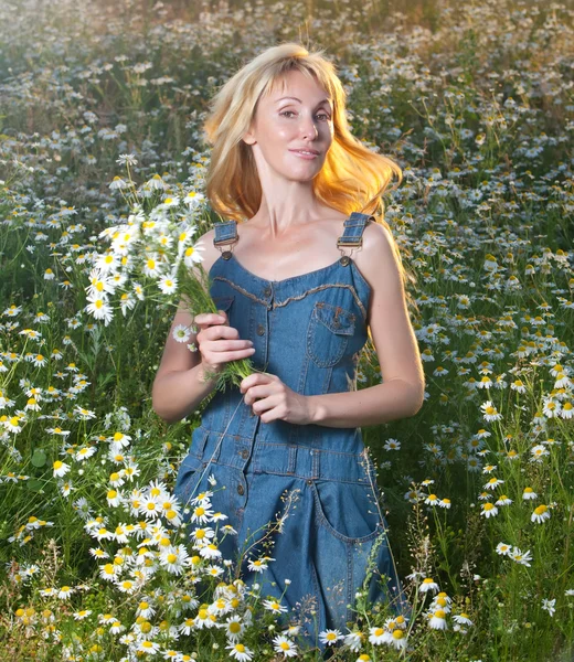 La belle jeune femme sur le terrain avec un bouquet de camomilles — Photo