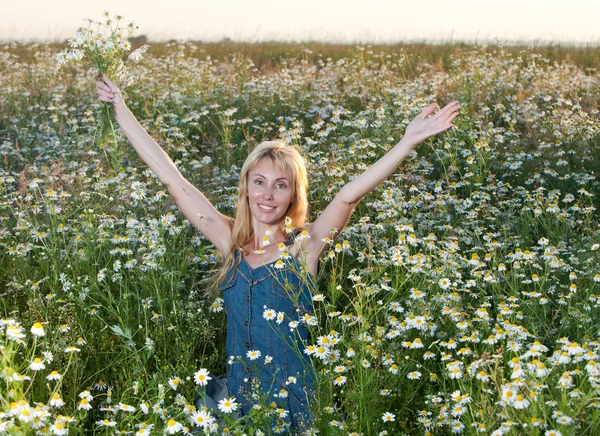 The beautiful young woman in the field with a bouquet of camomiles — Stock Photo, Image