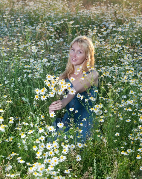 A bela jovem no campo com um buquê de camomilas — Fotografia de Stock