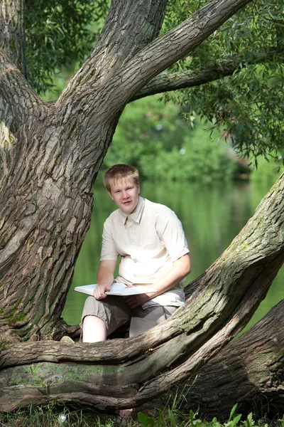 호수의 은행에 공원에서 책을 가진 젊은이 — 스톡 사진