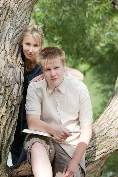 Young guy and the girl prepare for lessons, examination in spring park near lake — Stock Photo, Image