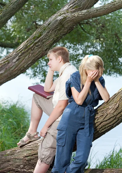 Young guy and the girl prepare for lessons, examination in spring park near lake — Stock Photo, Image