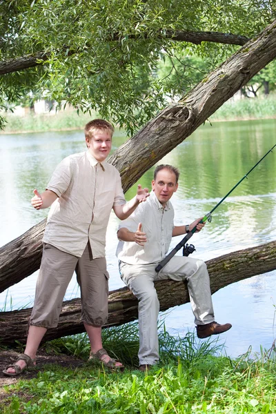 Отец с сыном на рыбалке, показывает размер рыбы — стоковое фото