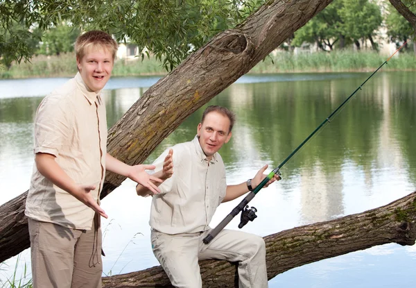 The father with the son on fishing, shows the size of fish — Stock Photo, Image