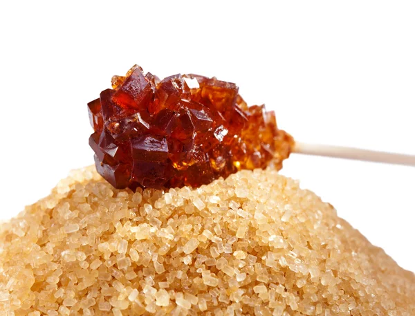Açúcar doce marrom em um pau e açúcar mascavo — Fotografia de Stock