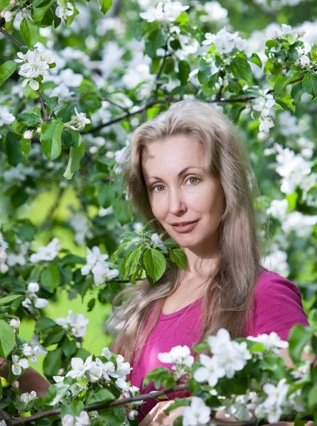 Jovem mulher atraente em pé perto da macieira florescente — Fotografia de Stock