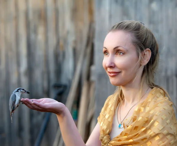Piękna młoda kobieta karmi ptaka z ręki — Zdjęcie stockowe
