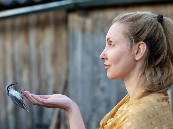 La joven mujer hermosa alimenta a un pájaro de una mano — Foto de Stock