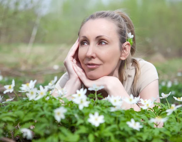 The young beautiful woman on a glade of blossoming snowdrops in the early sprin — Stock Photo, Image