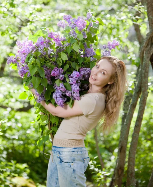 Giovane donna felice in parco con un mazzo grande di un lilla — Foto Stock