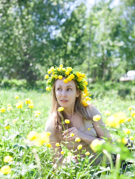 Den unga vackra kvinnan i en krans från globeflower i fältet — Stockfoto