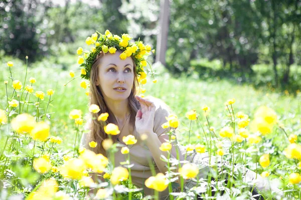 La mujer joven hermosa en una corona de Globeflower en el campo — Foto de Stock