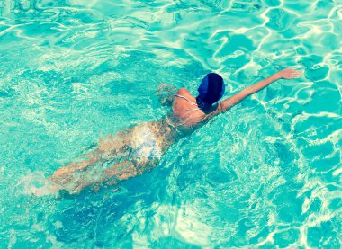 Spor kadın retro etkisi ile parlak mavi suda yüzüyor.