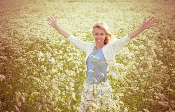 白い野生の花のレトロな効果を持つフィールドで幸せな若い女 — ストック写真