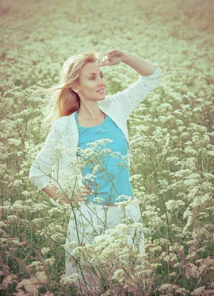 The happy young woman in the field of white wild flowers,with a retro effect — Stock Photo, Image