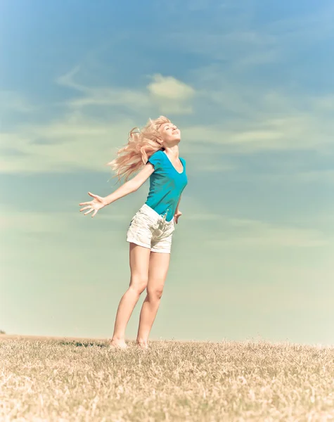 Счастливая женщина в летнем поле против голубого неба, с ретро-эффектом — стоковое фото