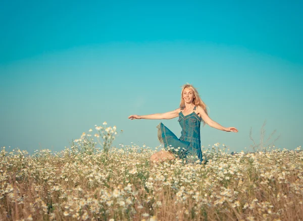 Wanita muda yang bahagia melompat di lapangan camomiles, dengan efek retro — Stok Foto
