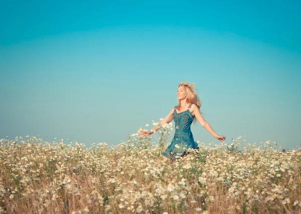 La joven feliz salta en el campo de las manzanillas, con un efecto retro —  Fotos de Stock
