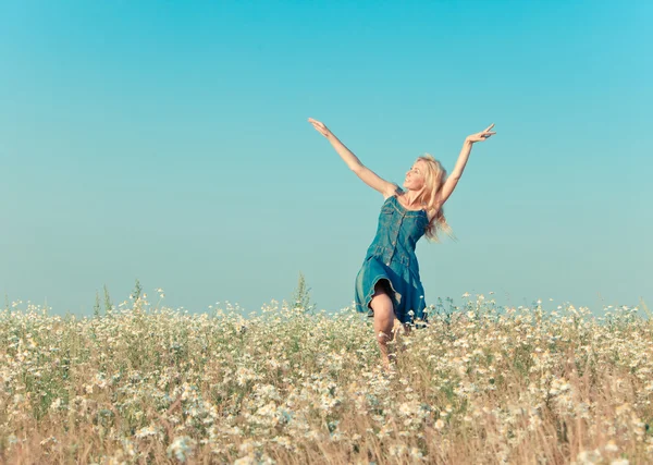 La joven feliz salta en el campo de las manzanillas, con un efecto retro —  Fotos de Stock