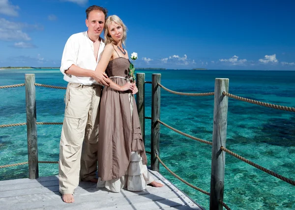 Casal amoroso em uma plataforma de madeira sobre o mar na ilha tropical — Fotografia de Stock
