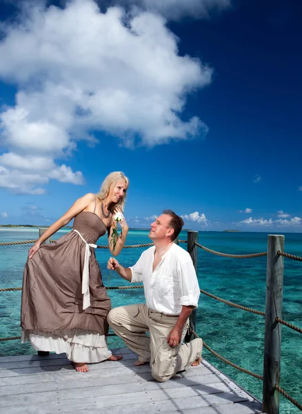 Casal amoroso em uma plataforma de madeira sobre o mar na ilha tropical — Fotografia de Stock