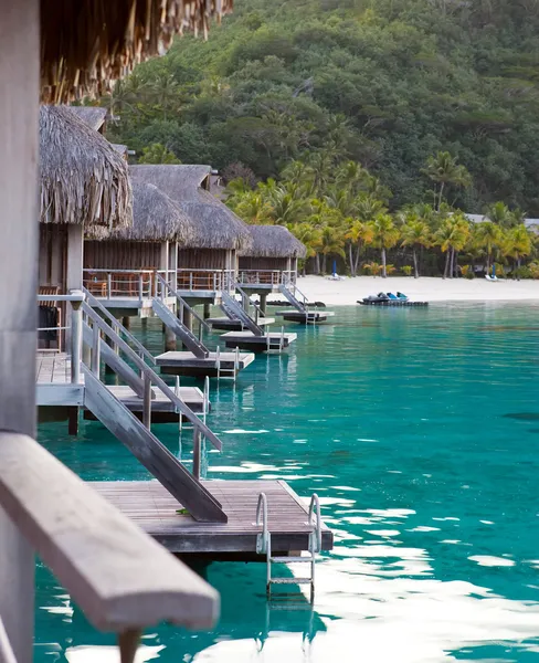 전형적 인 폴리네시아 풍경 - 야자나무와 물 위에 있는 작은 집들로 뒤덮인 해변 — 스톡 사진