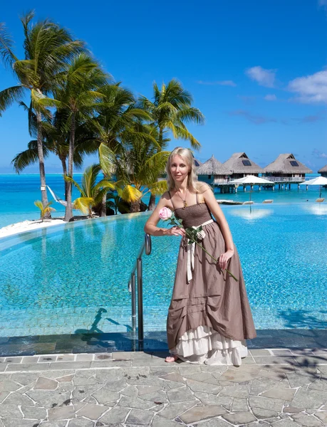 De jonge mooie vrouw in een romantische jurk met een roos op zand op de edg zee — Stockfoto