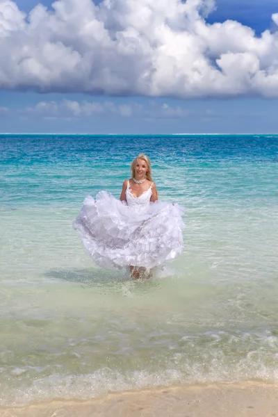 La bella donna giovane in un vestito della sposa corre su onde del mare — Foto Stock