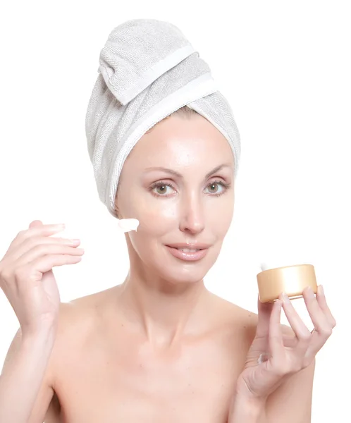 De mooie jonge vrouw in de handdoek met een cosmetische crème — Stockfoto