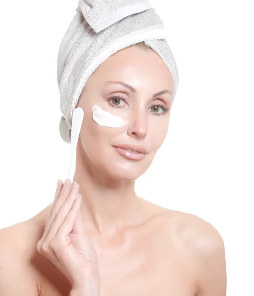 De mooie jonge vrouw in de handdoek met een cosmetische crème — Stockfoto