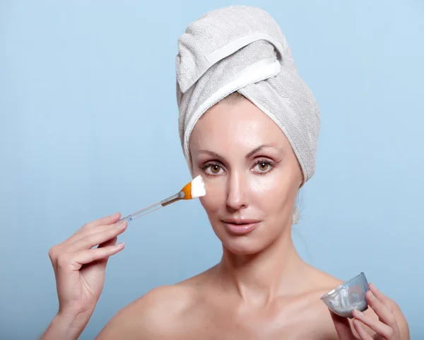 De mooie jonge vrouw in de handdoek met een cosmetische crème — Stockfoto