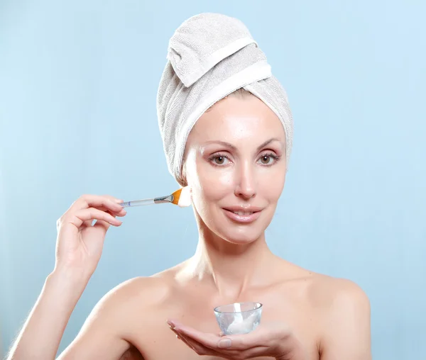 De mooie jonge vrouw in de handdoek met een cosmetische crème — Stockfoto