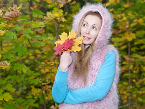 Красива жінка в осінньому парку з обладунками кленового листя — стокове фото