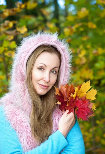 Die schöne Frau im Herbstpark mit einem Arm voller Ahornblätter — Stockfoto