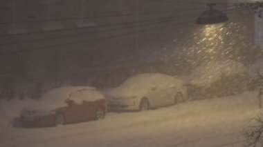 Geceleri şehirde kar yağıyor, kar fırtınası sokak ışıklarıyla aydınlanıyor, kötü hava.,
