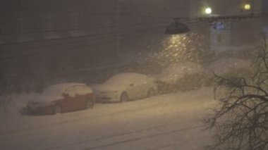 Geceleri şehirde kar yağışı, sokak ışıklarıyla aydınlanan kar fırtınası, kötü hava, 4K UHD 'de çekim.