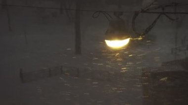 Geceleri şehirde kar yağışı, sokak ışıklarıyla aydınlanan kar fırtınası, kötü hava, 4K UHD 'de çekim.