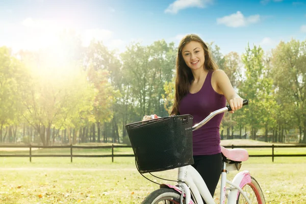 Menina alegre com uma bicicleta — Fotografia de Stock
