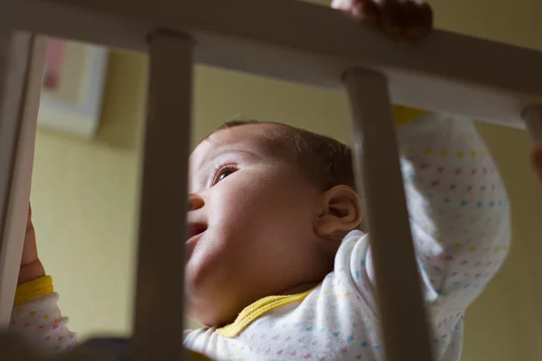 Cute baby girl in her cot — Stock Photo, Image